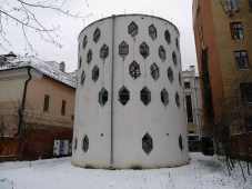 Squat white cylindrical building with rows of jewel shaped windows